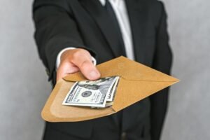 manos entregando un sobre de dinero