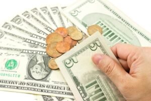 manos sosteniendo billetes y monedas dolares